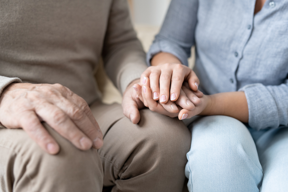 Hand of senior man in casualwear between those of his affectionate daughter